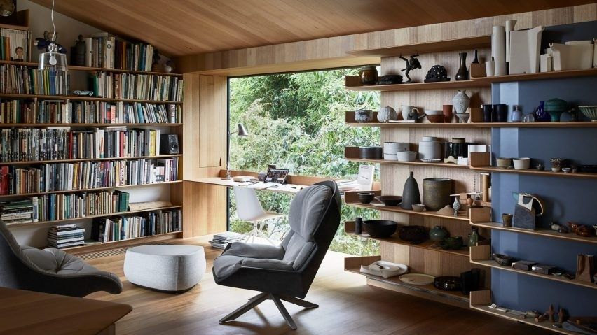 Compact home library with bookshelves, a reading chair, and pottery displays