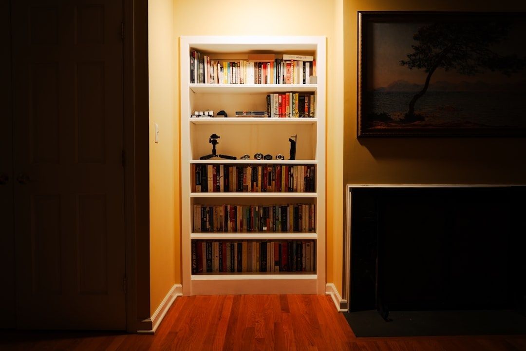 Compact white bookshelf filled with books beside a fireplace