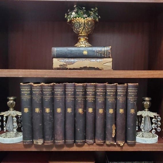 Antique cloth-bound books and decorative objects on a wooden shelf