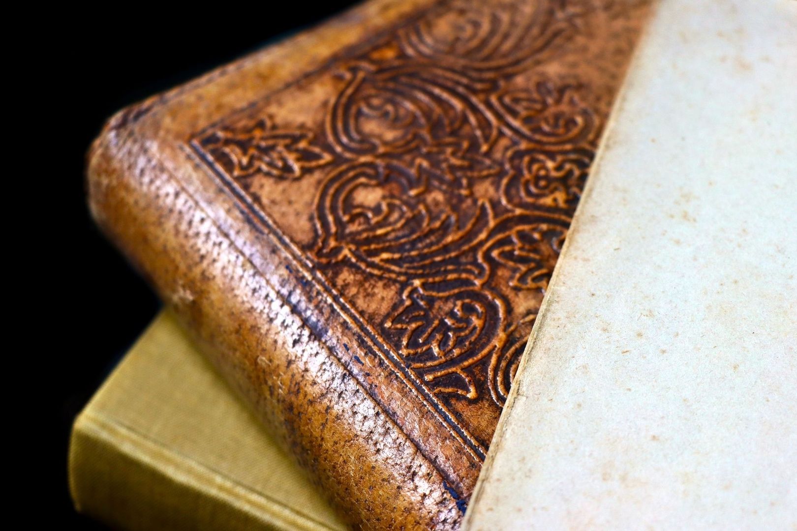 Close-up of an ornate leather-bound book beside pale pages